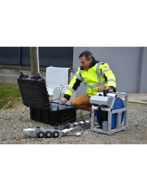 Technicien en tenue haute visibilité préparant la valise de commande et le câble d'un chariot caméra ITV sur un chantier d'inspection